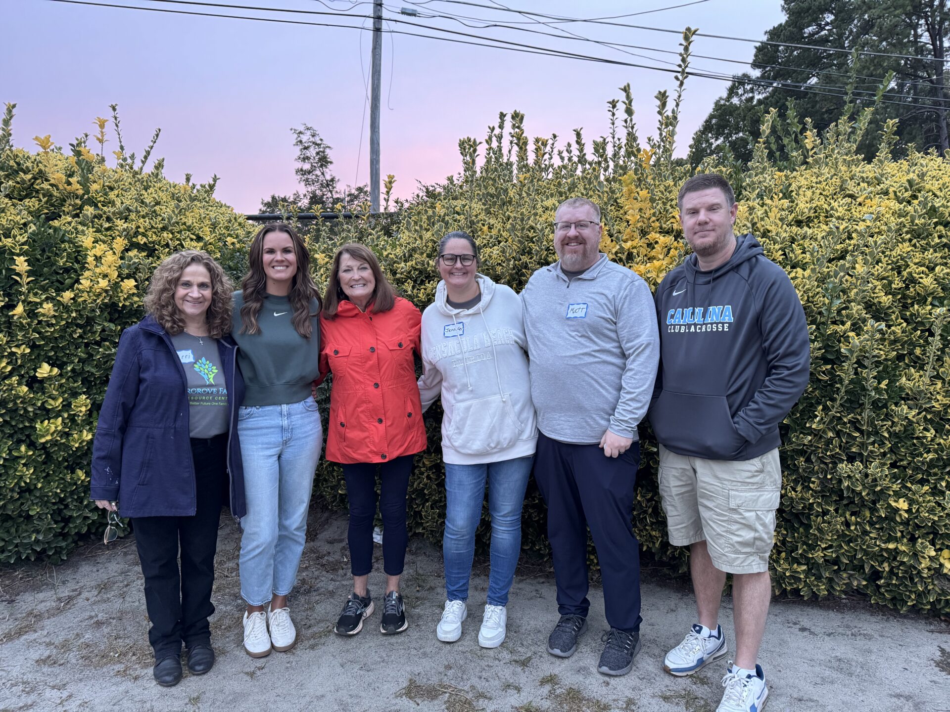 Group of six people smiling outdoors together.